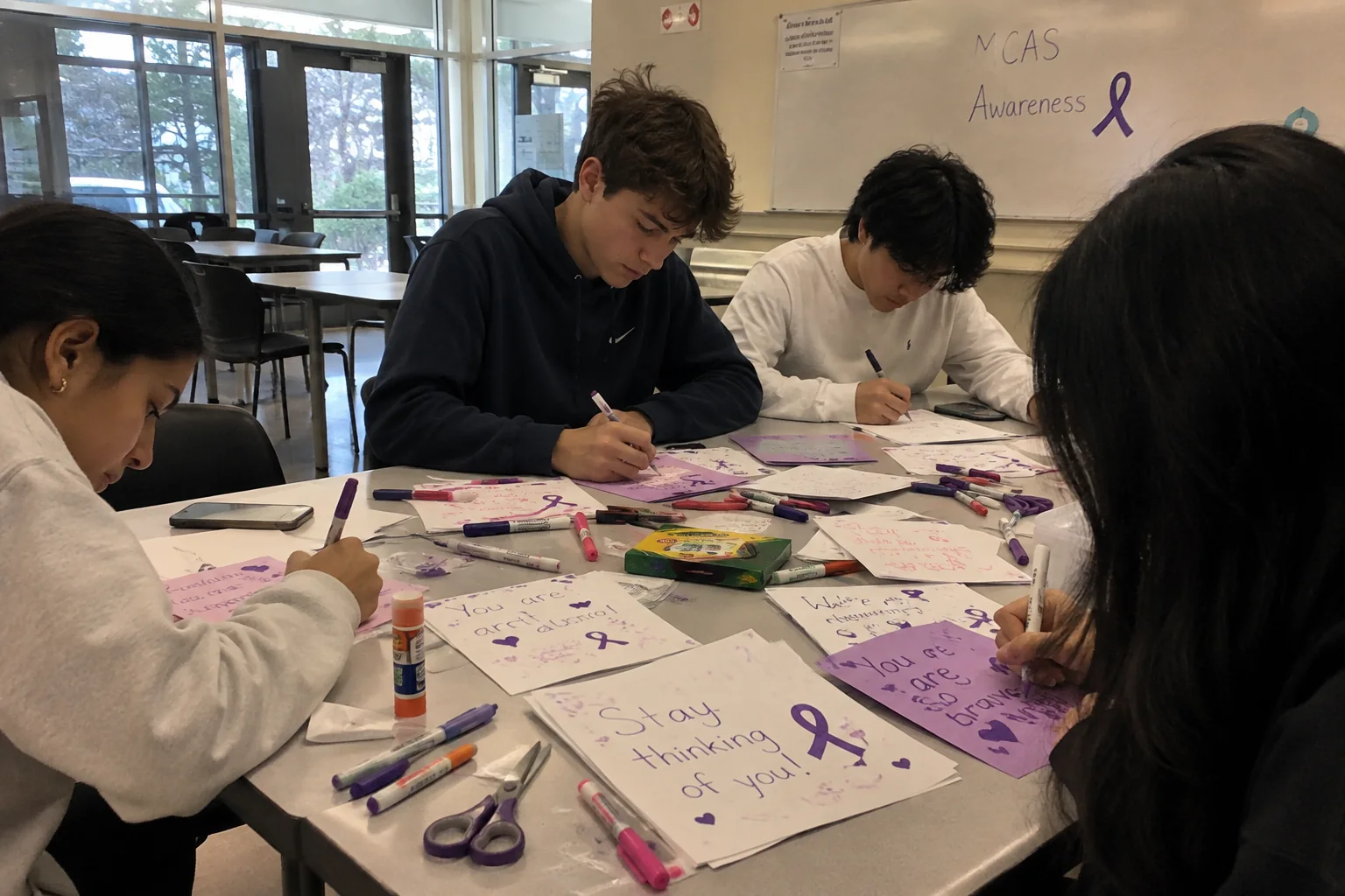 Volunteers writing and illustrating MCAS inspiration cards together at a table